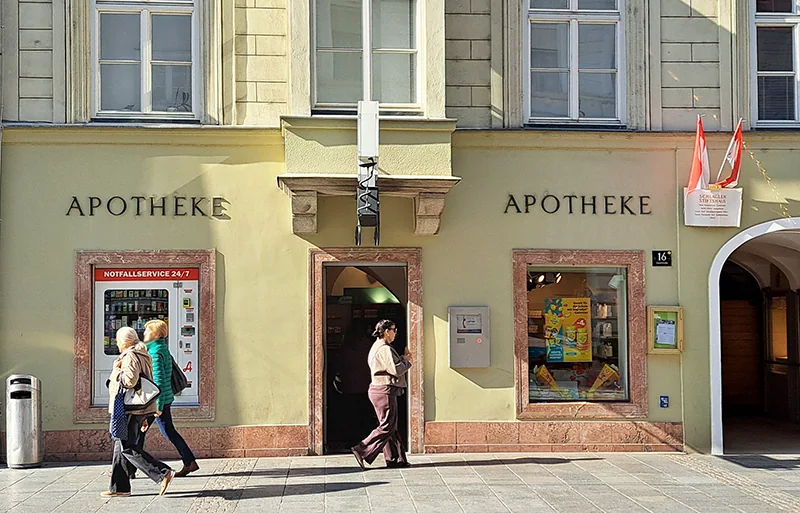 Geschäftsportal der Apotheke „Zum Schwarzen Adler“ an der Landstraße 16 mit zwei „Apotheke“-Schriftzügen und Passanten