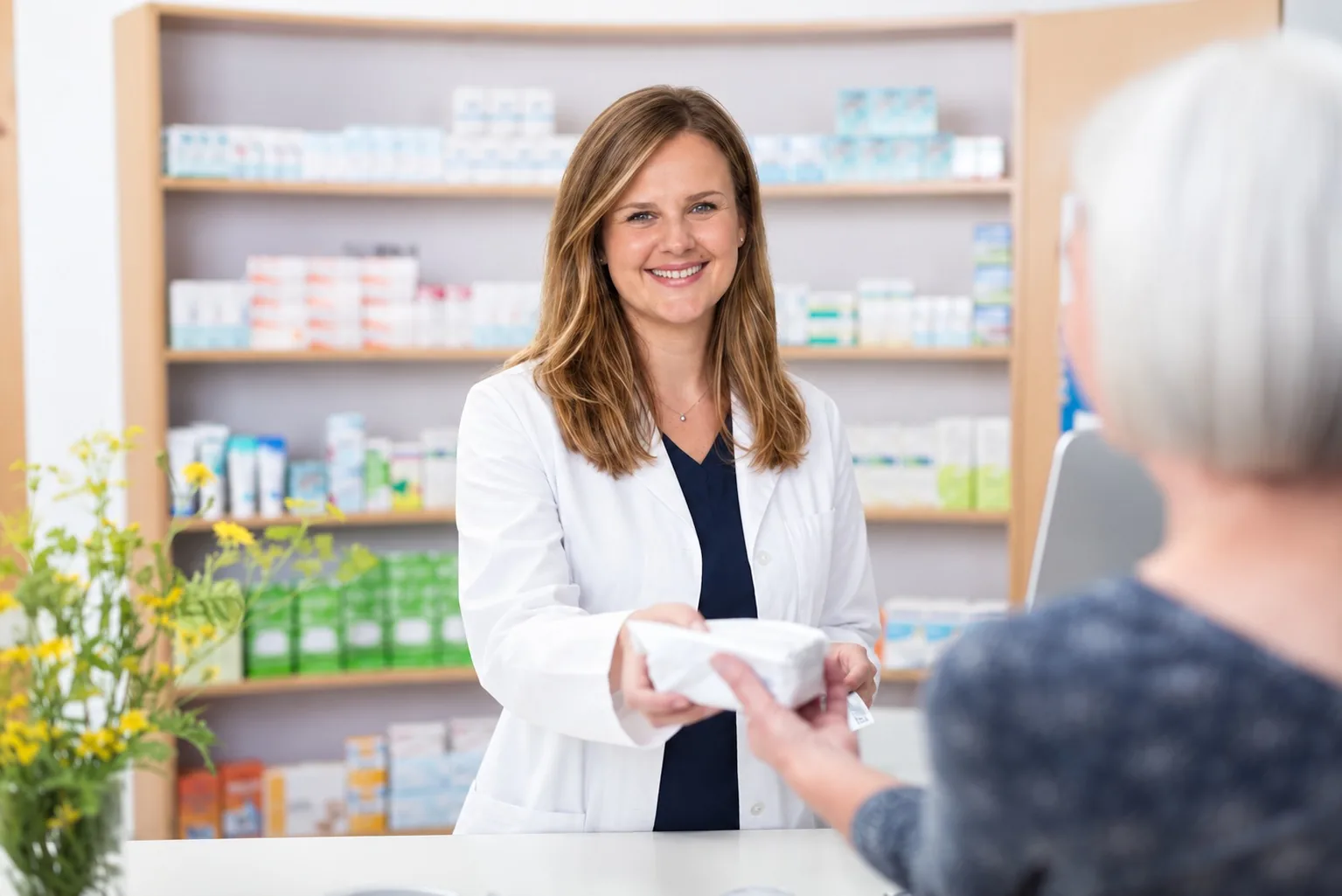 Apothekerin Florina-Ioana Colesnicov reicht in der Apotheke einer Kundin ein Arzneimittel über den Verkaufstisch